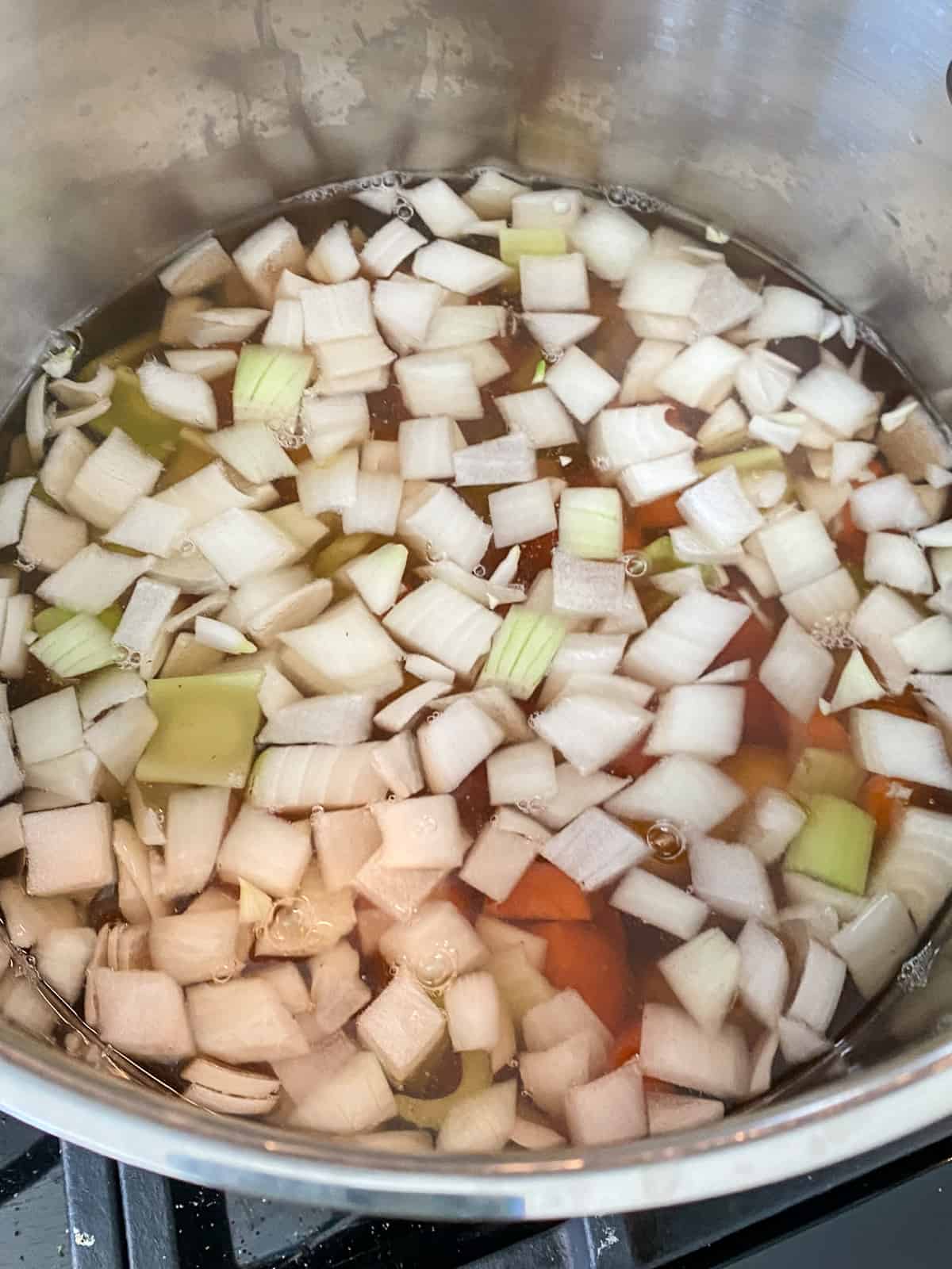 Vegetable stock and chopped vegetables in a large pot.