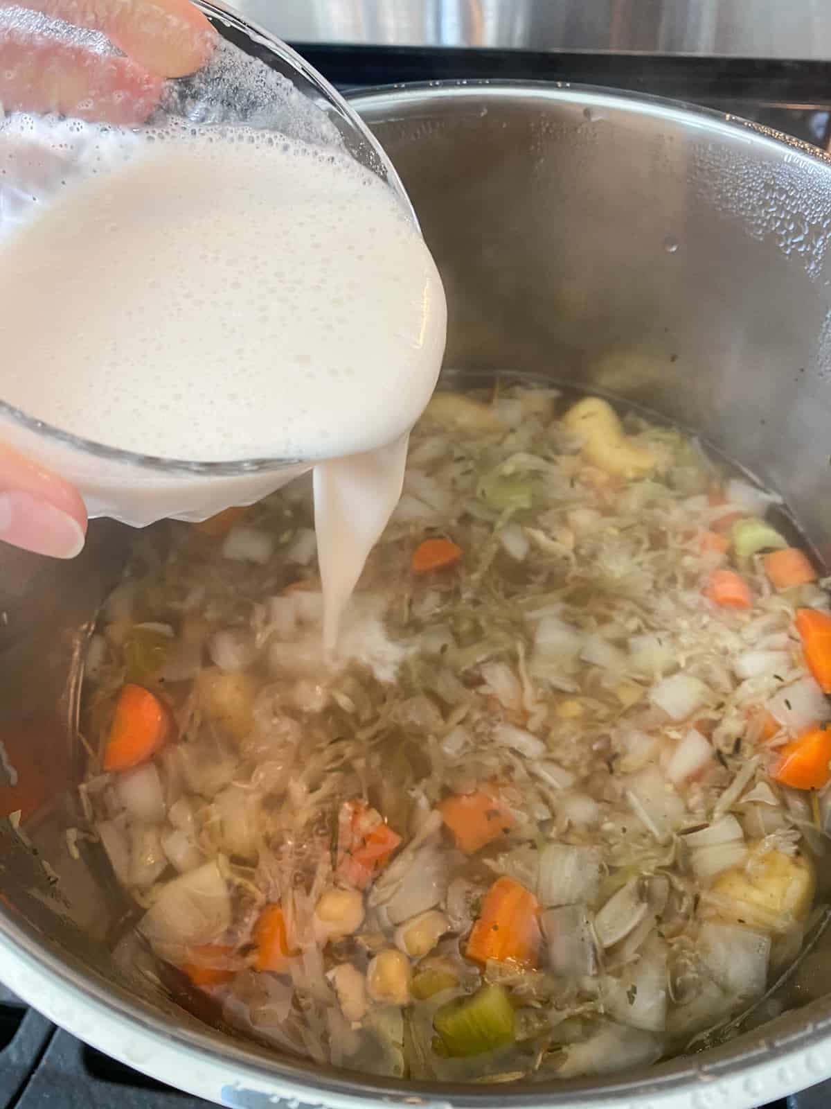 Pouring a mixture of cold water and flour into the stew to thicken it.