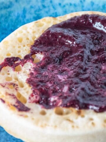 Close up of blueberry chia jam smeared on a toasted crumpet.