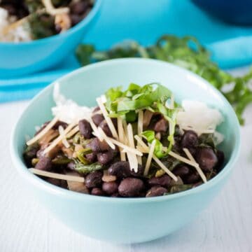 Bowl of black beans and rice, garnished with fresh basil and shredded parmesan cheese.