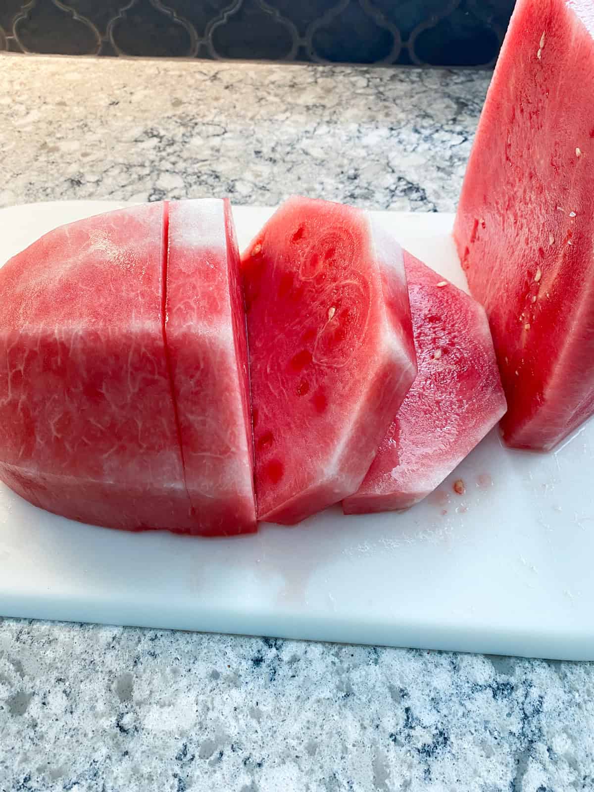 Flesh of a watermelon, sliced, on a cutting board.