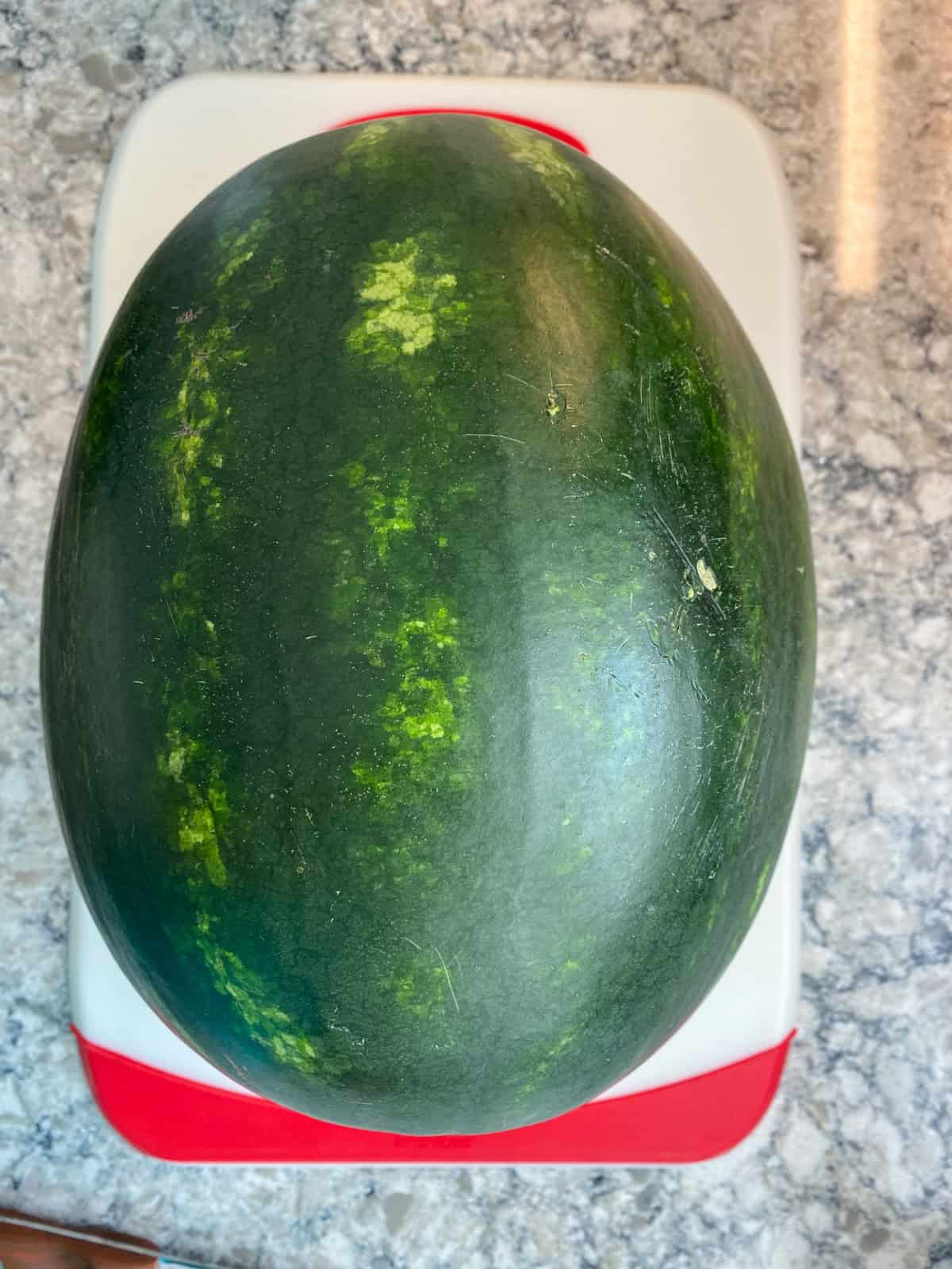 Whole watermelon on a cutting board.