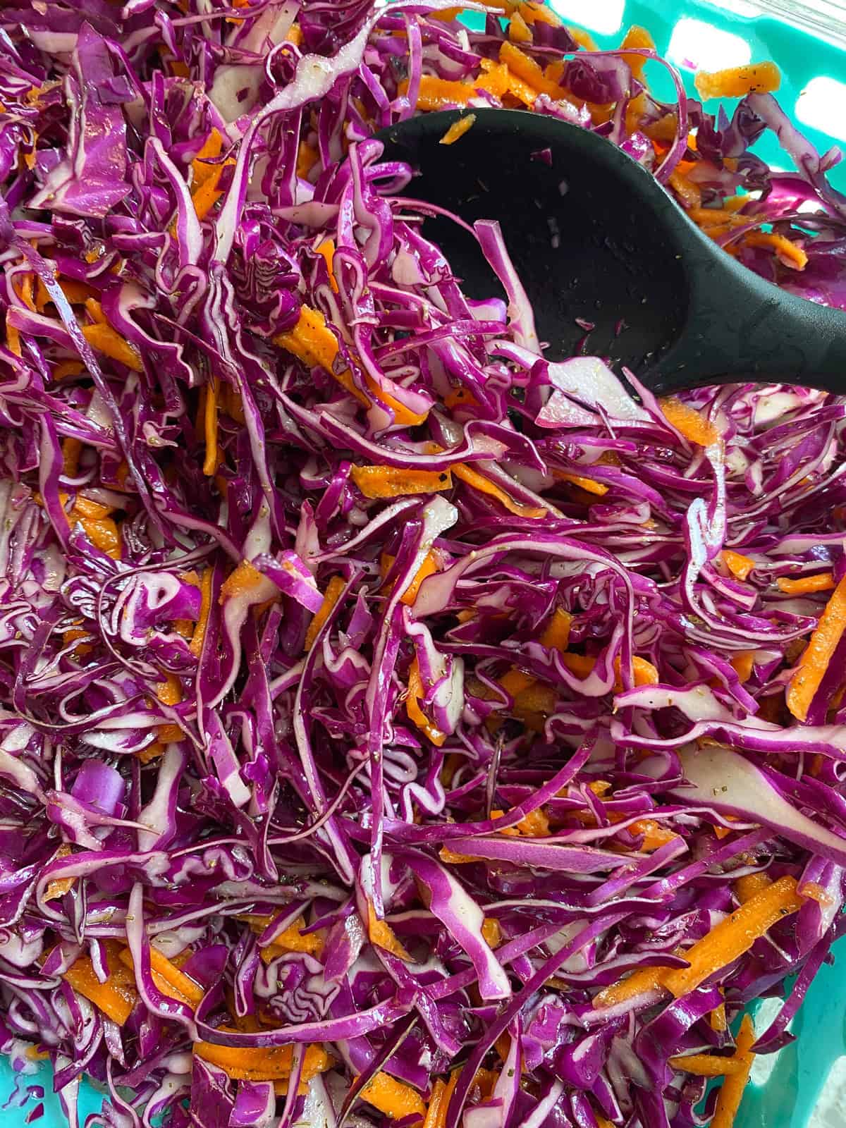 Dressing mixed into shredded red cabbage and carrots.