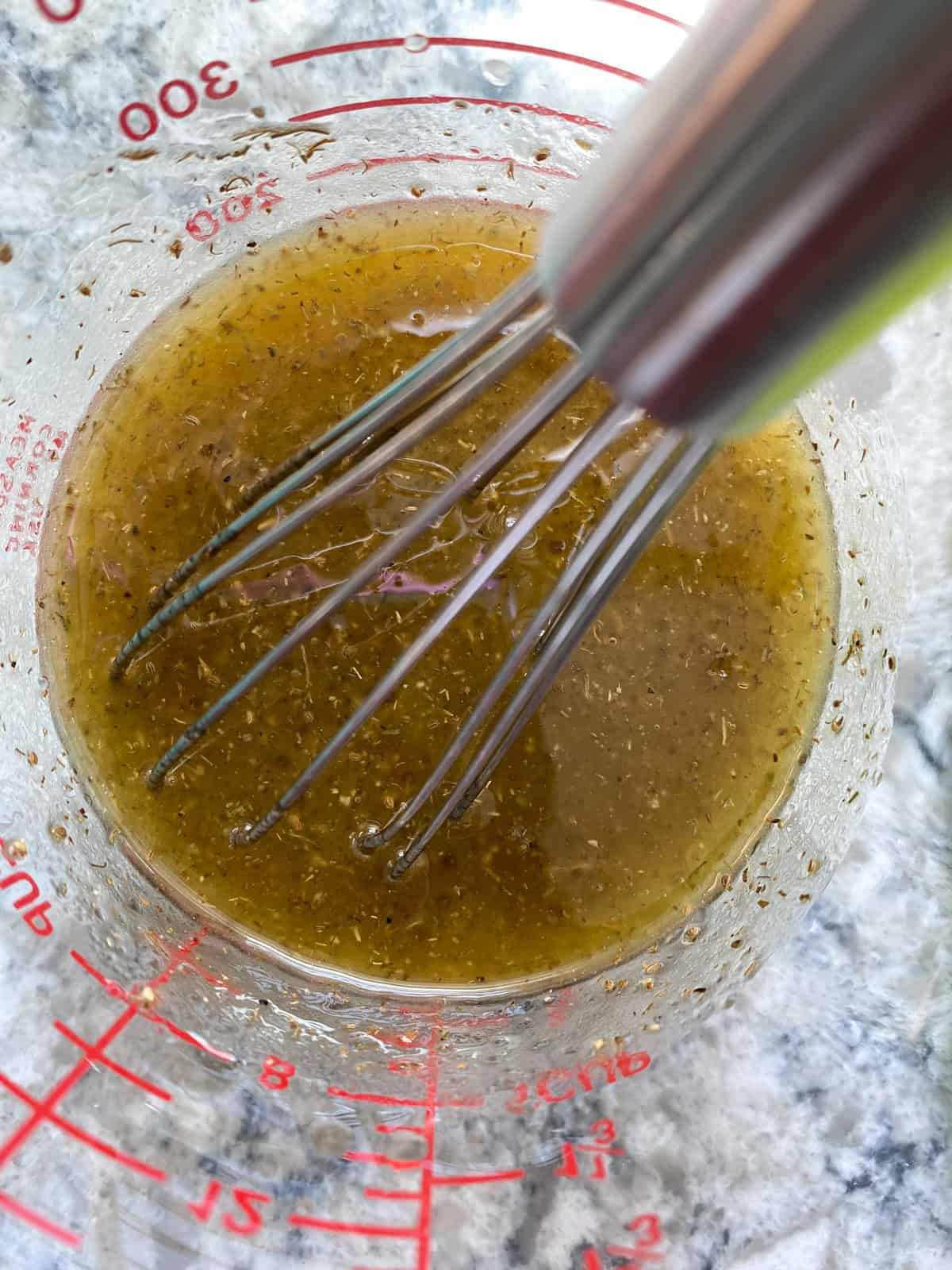 Whisked dressing for red cabbage slaw in a liquid measuring cup.
