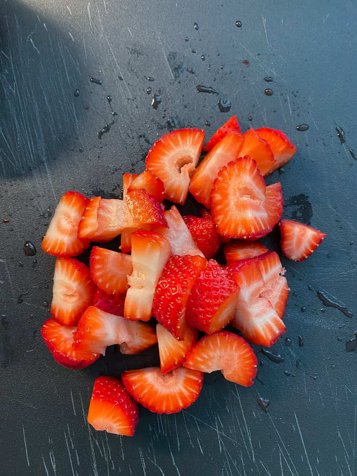 Chopped strawberries on a cutting board.