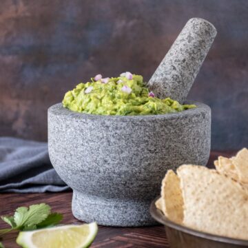 Large stone mortar and pestle filled with guacamole.