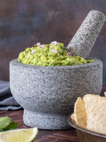 Large stone mortar and pestle filled with guacamole.