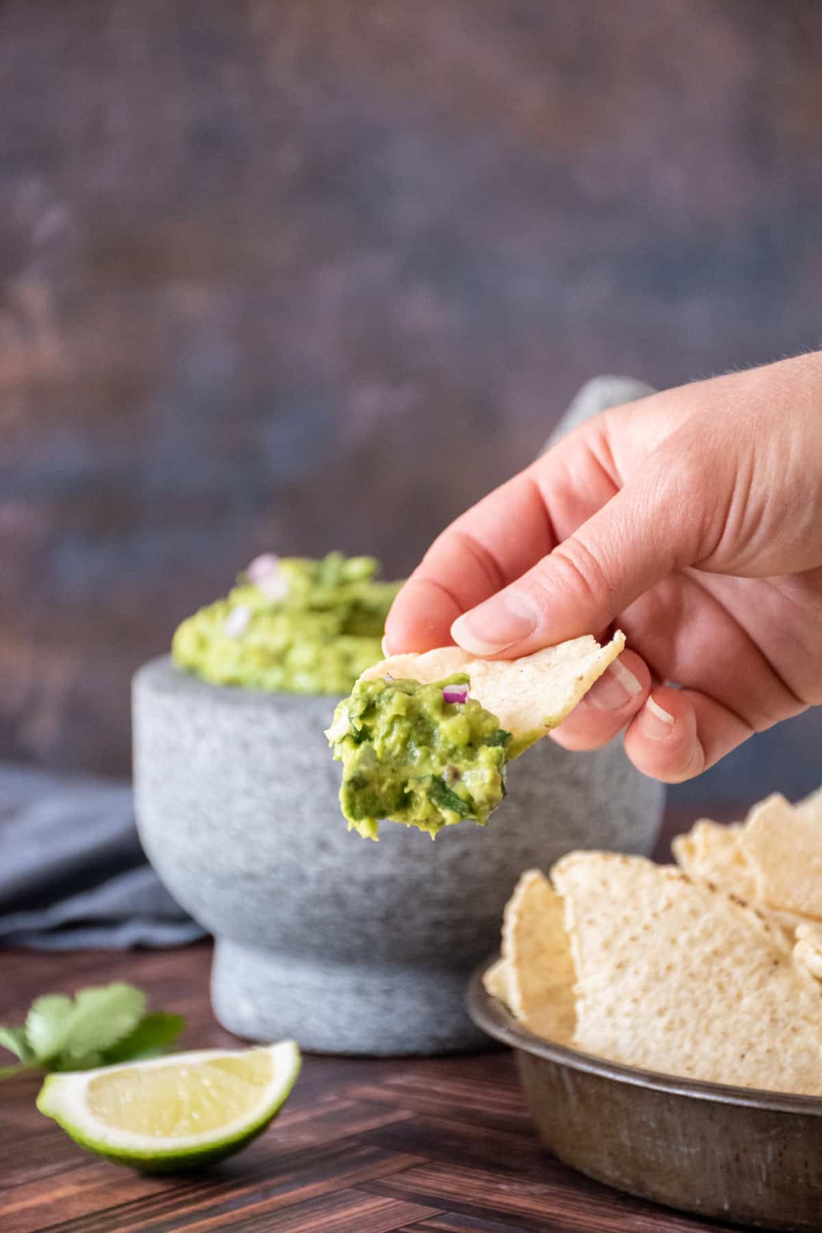 Close up of a tortilla chip with guacamole on it.