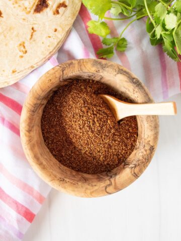 Small wooden bowl with taco seasoning in it, and a wooden spoon.