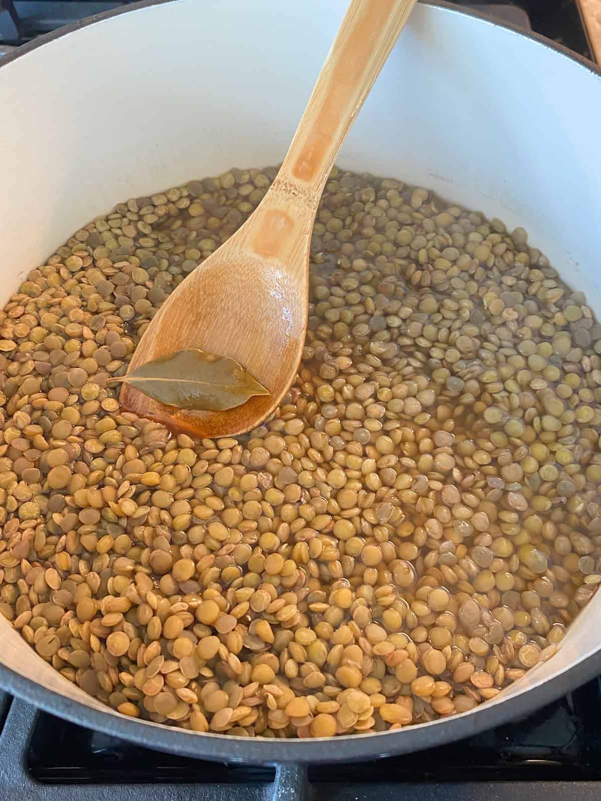 Bay leaf being removed from cooked lentils.
