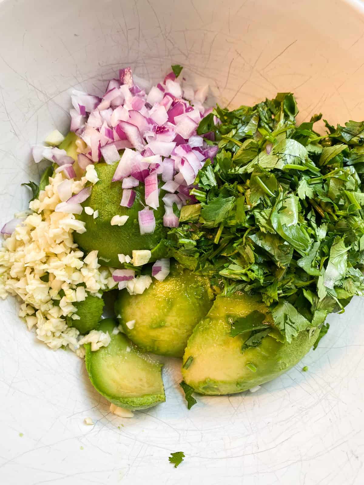 Whole, unmashed ingredients for guacamole in a bowl.