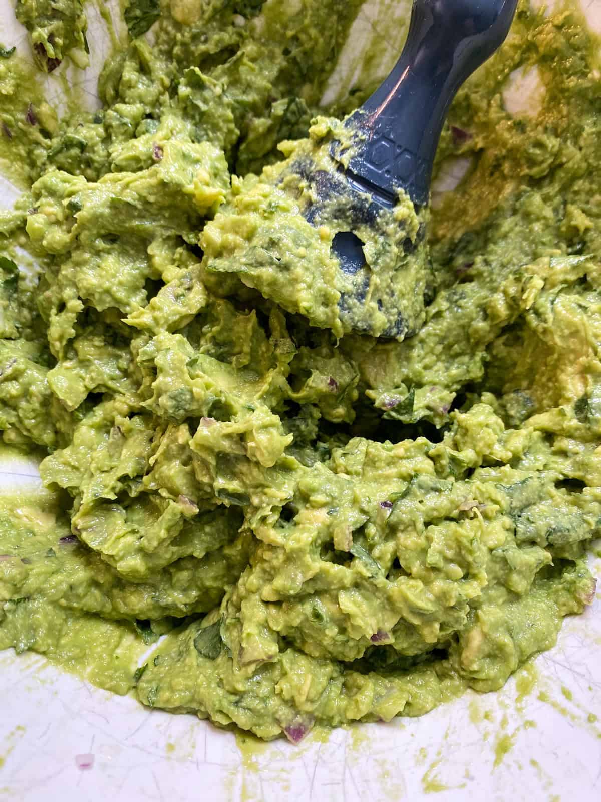 All ingredients mashed into guacamole, in a bowl.