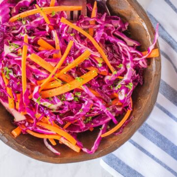 Wooden bowl with red cabbage coleslaw in it.