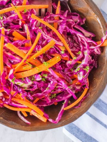 Wooden bowl with red cabbage coleslaw in it.