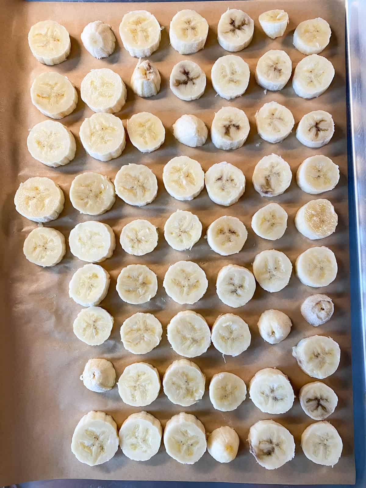 Slices on banana on a parchment lined baking sheet.