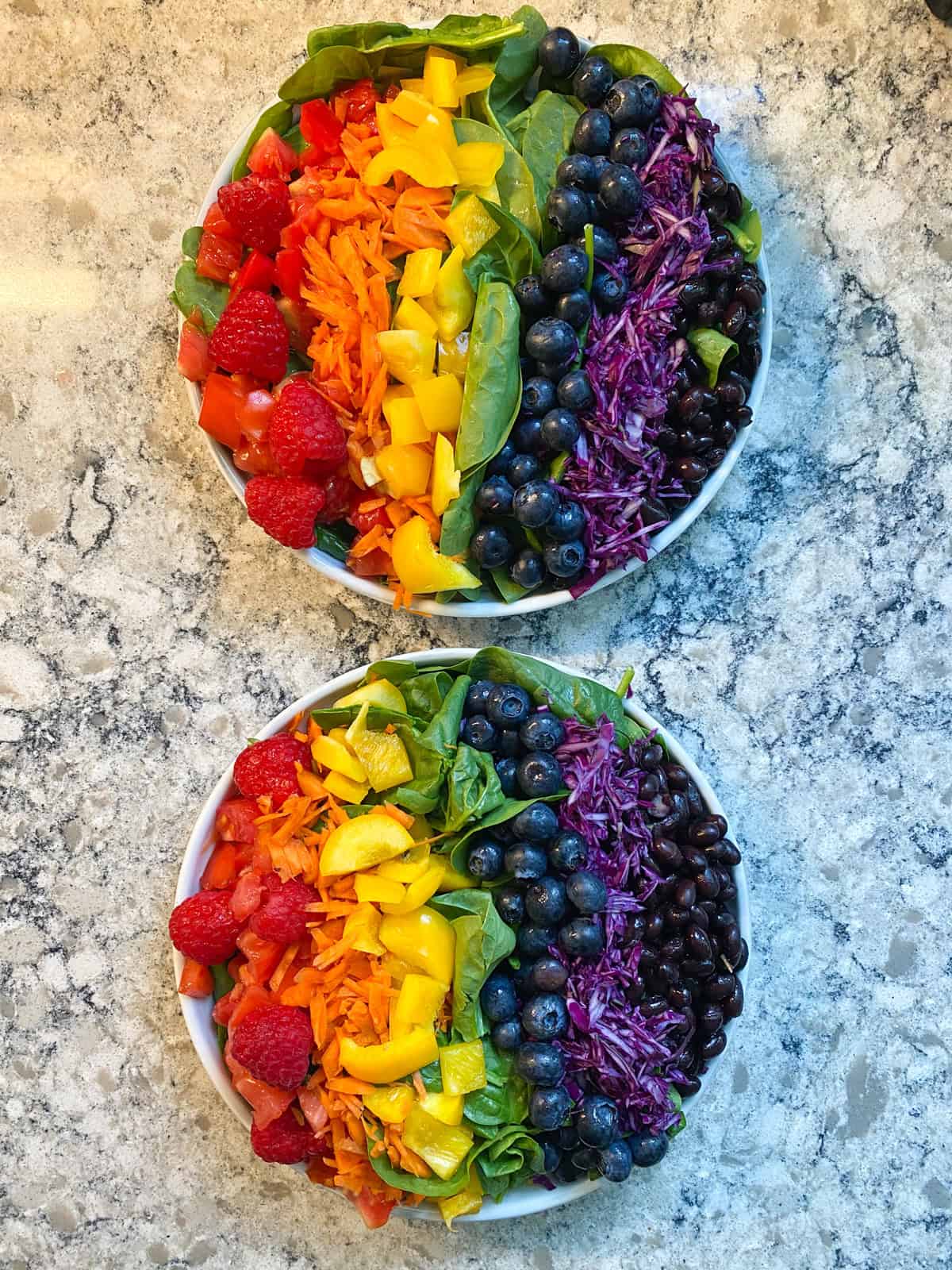 Two plates of salad with a column of blueberries place beside the cabbage.