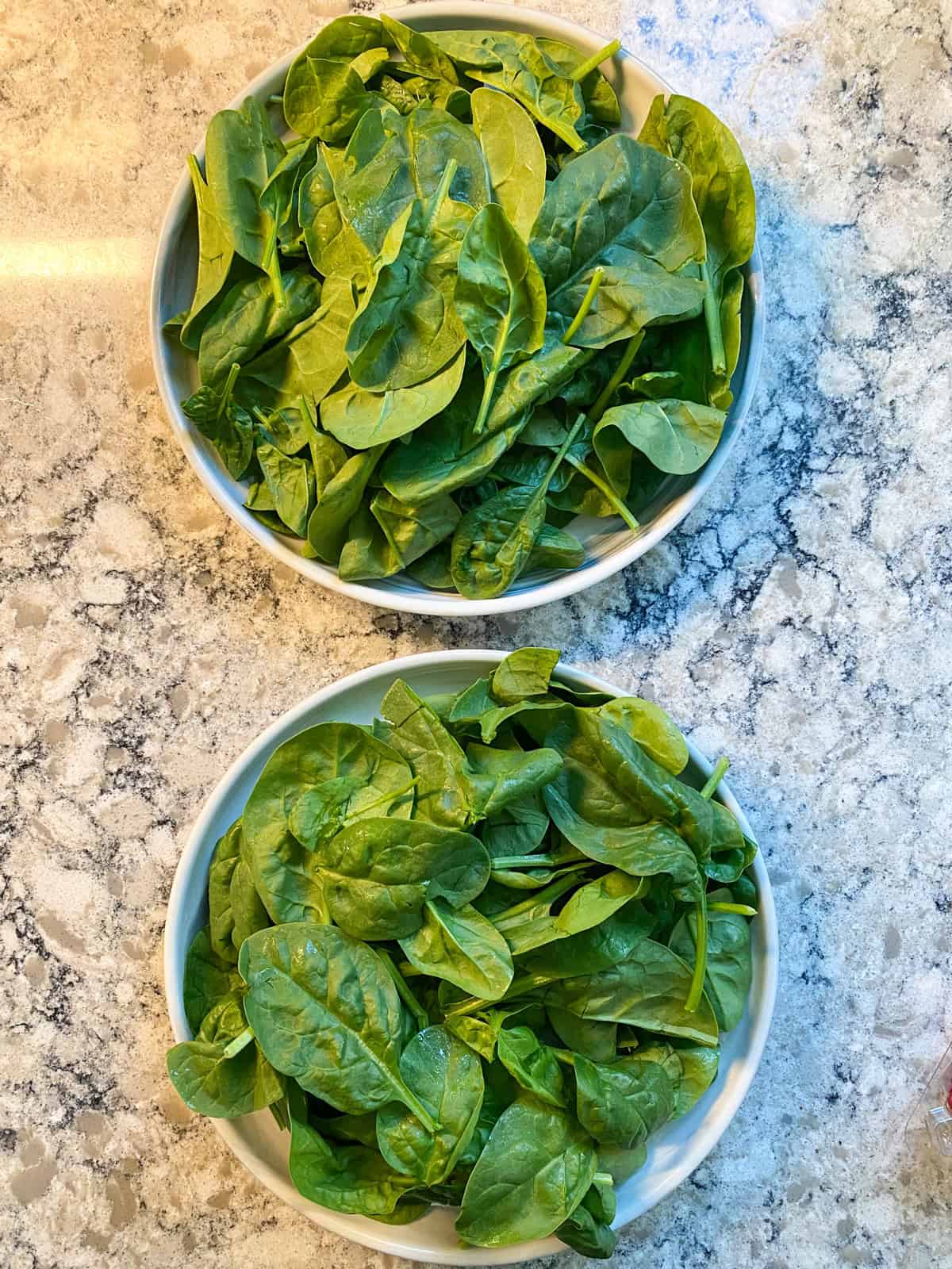Two salad plates with spinach on them.