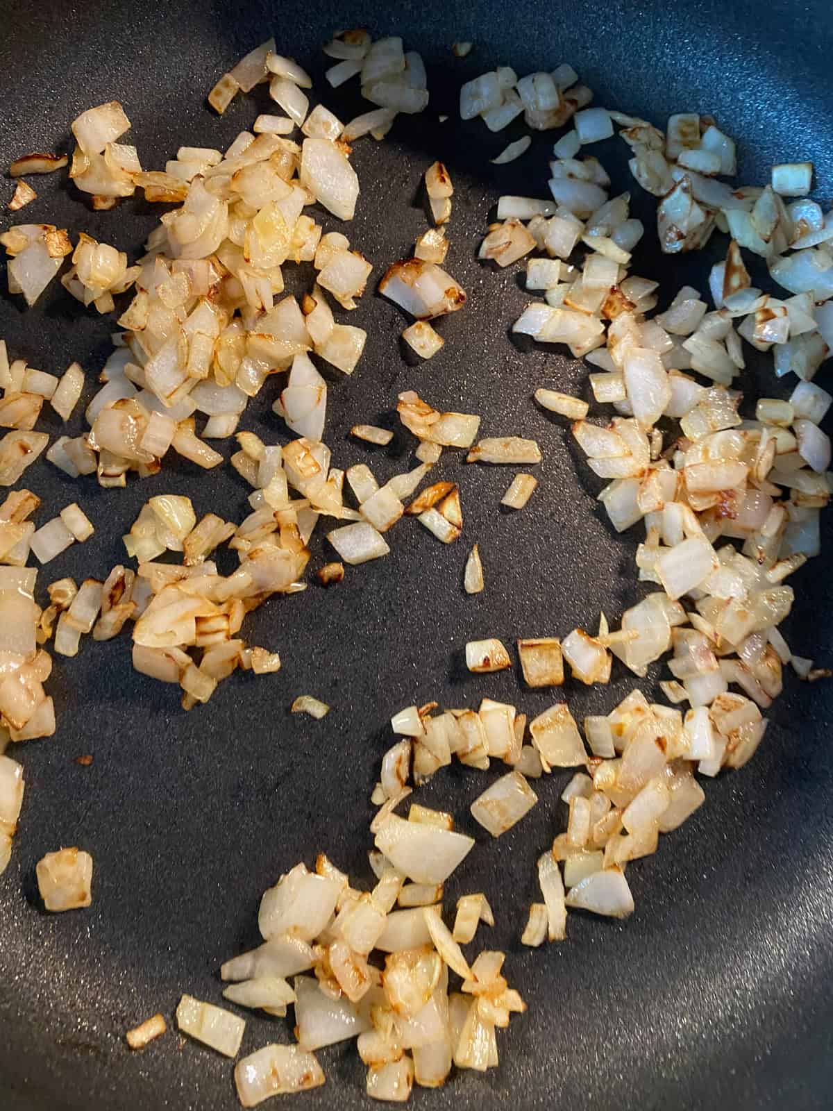 Onions in a pan, sauteed until browned and almost crispy.