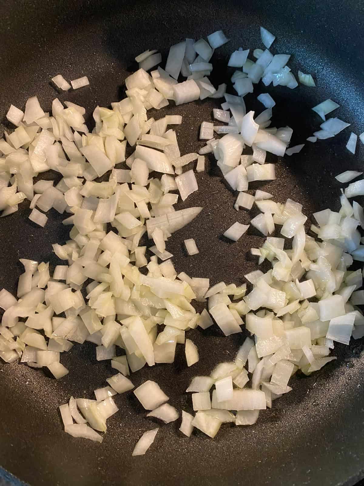 Chopped onions sauteing in a pan.