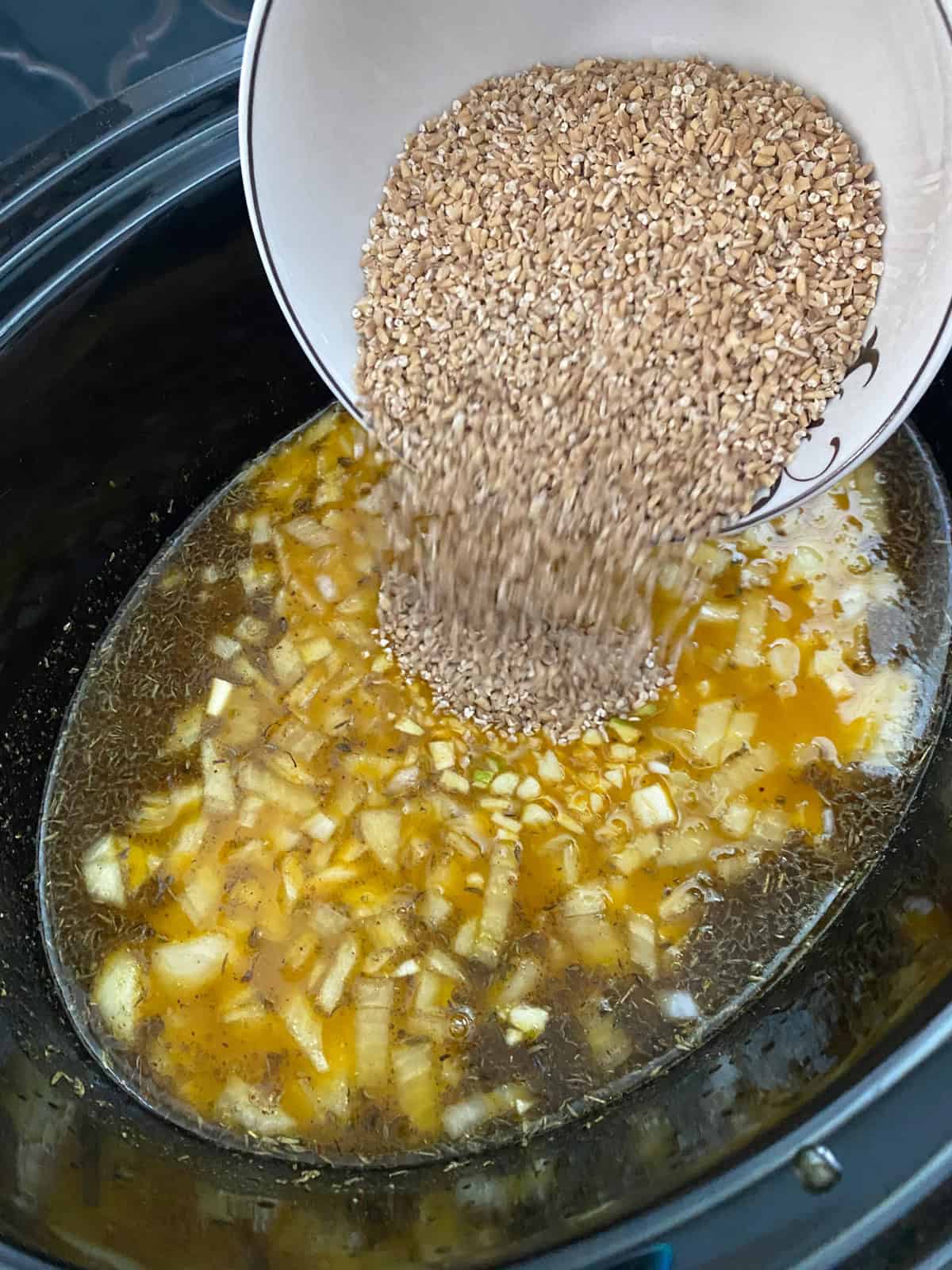 Steel cut oats being poured into the rest of the risotto ingredients.