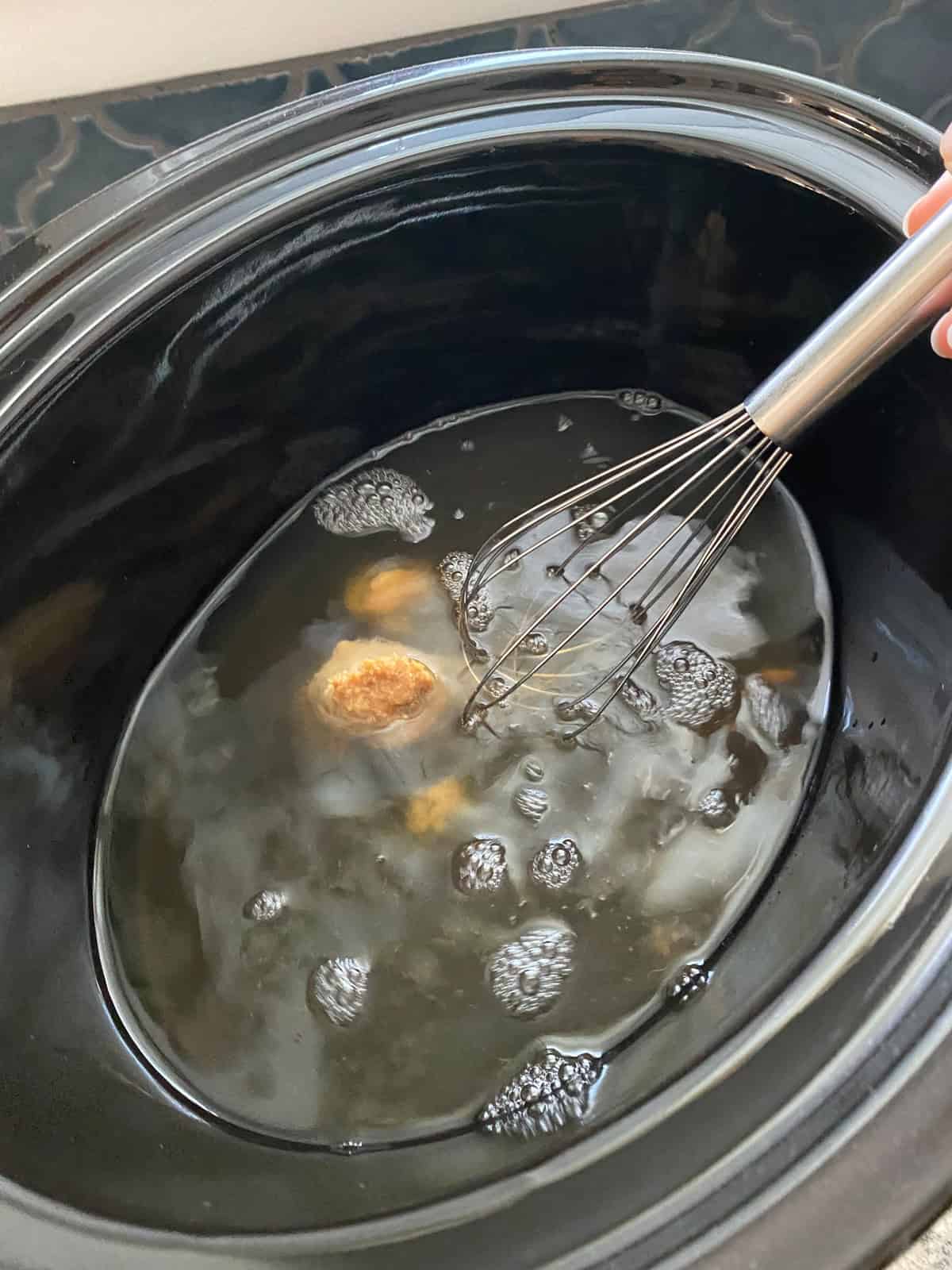 Vegetable stock and miso paste in a slow cooker.