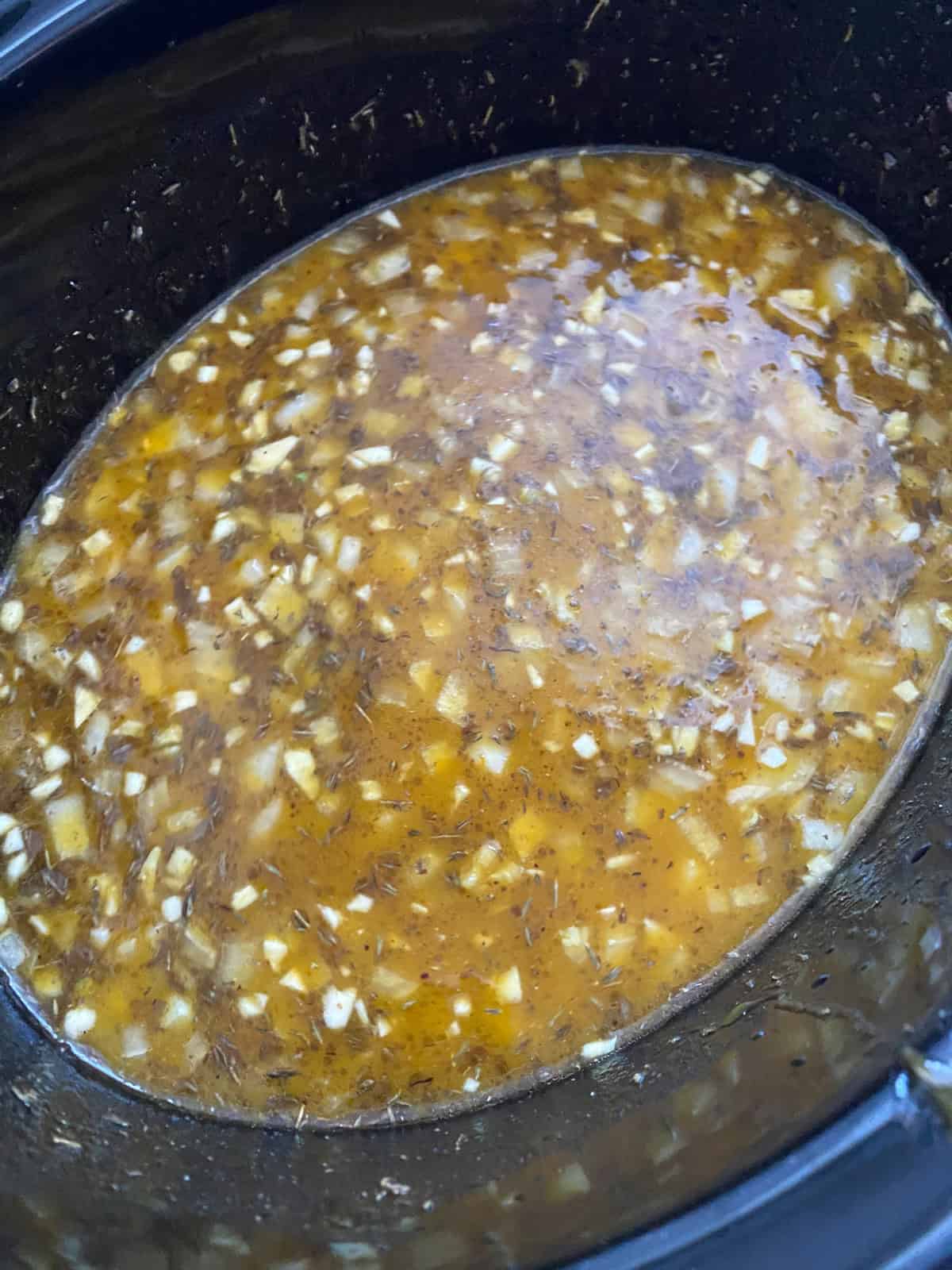 All risotto ingredients mixed together in a slow cooker crock.
