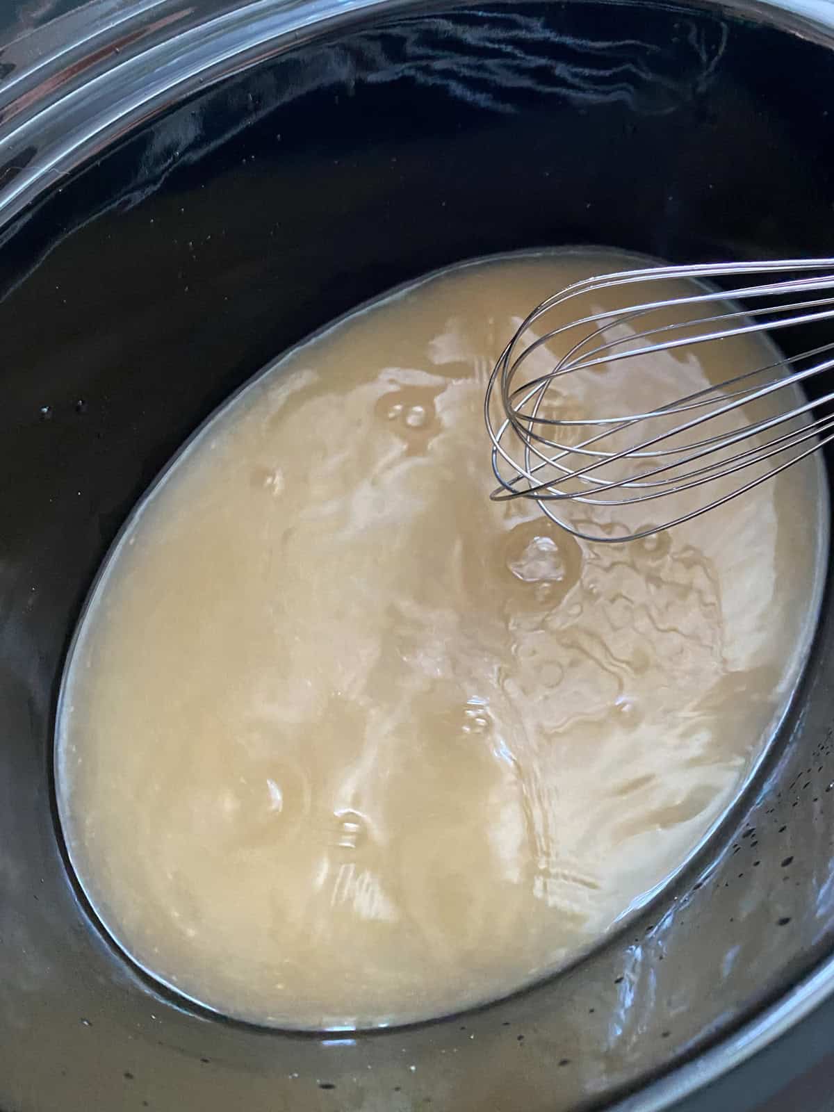 Slow cooker crock with vegetable stock and miso paste whisked together.