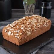 Whole, unsliced loaf of bread, sprinkled with oats.