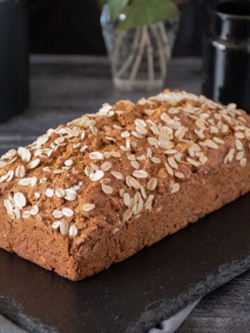 Whole, unsliced loaf of bread, sprinkled with oats.