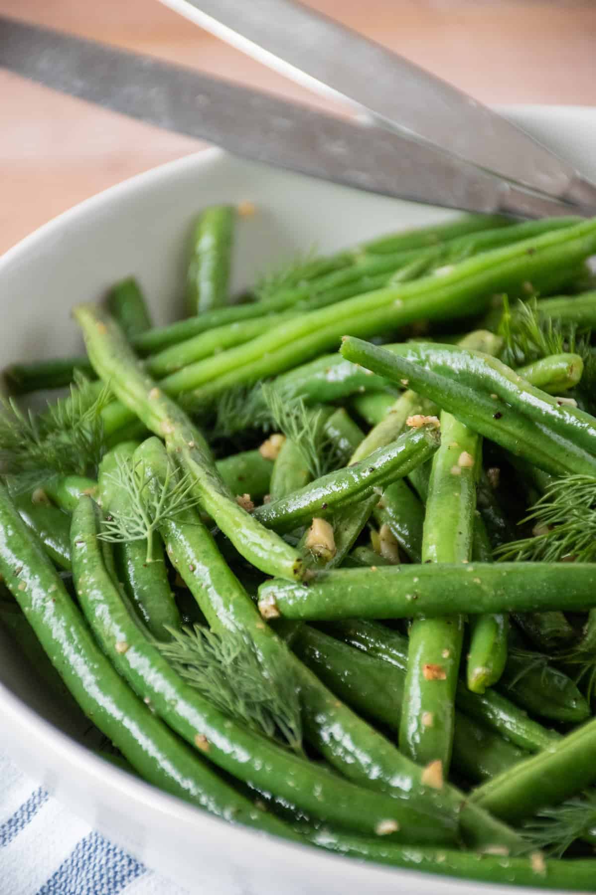 Roasted green beans in a bowl, garnished with fresh dill.