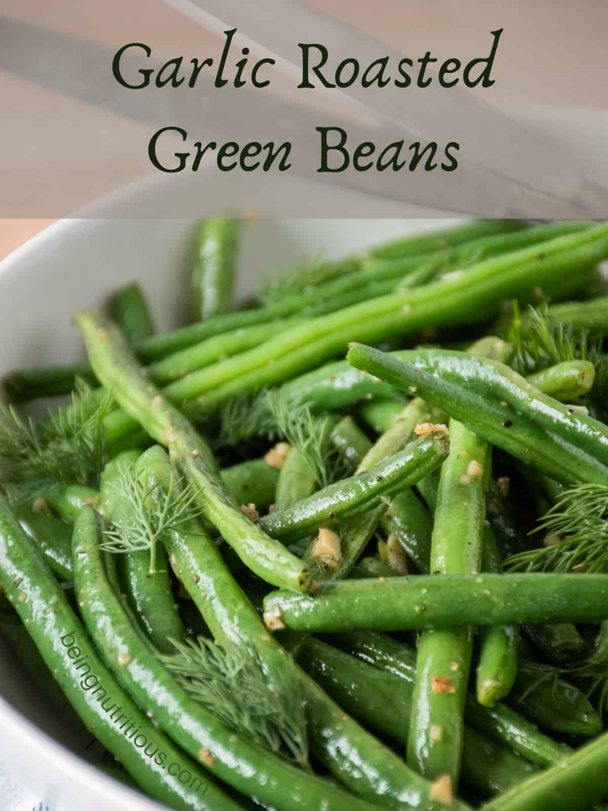 Roasted green beans in a bowl, garnished with fresh dill. Text overlay: Garlic Roasted Green Beans.