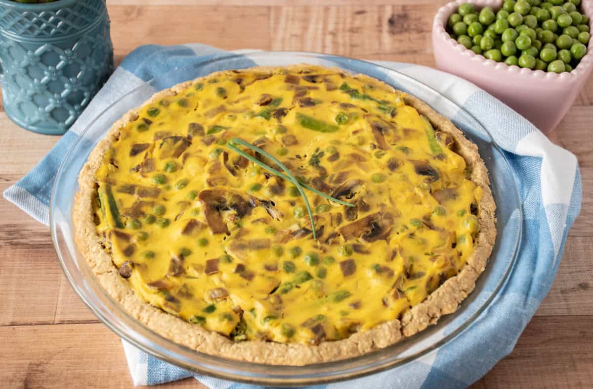 Whole eggless quiche in a pie plate, garnished with chives.