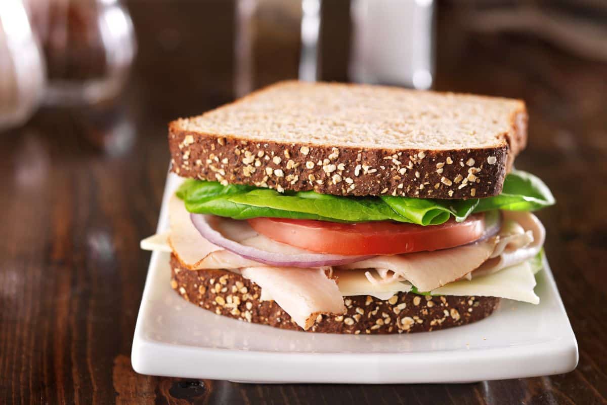 Sandwich made from deli meat, cheese, lettuce, onion, and tomato.