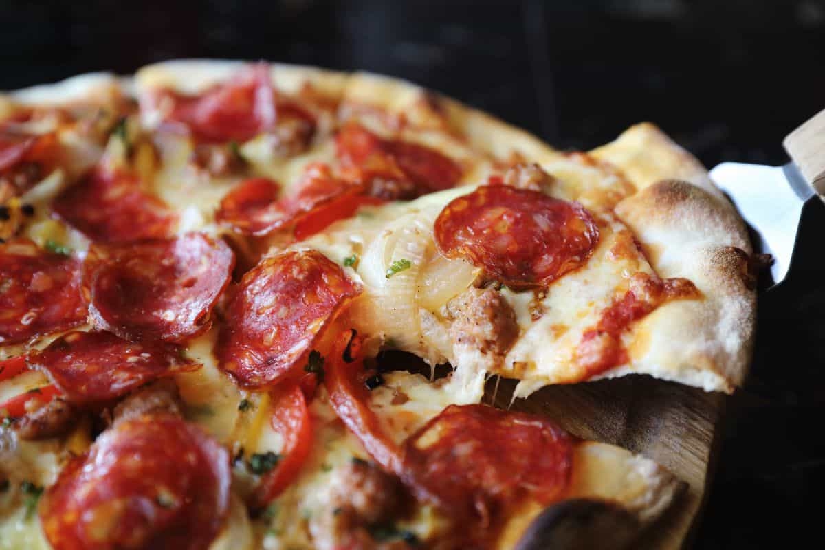 Pepperoni pizza with one slice being lifted away.