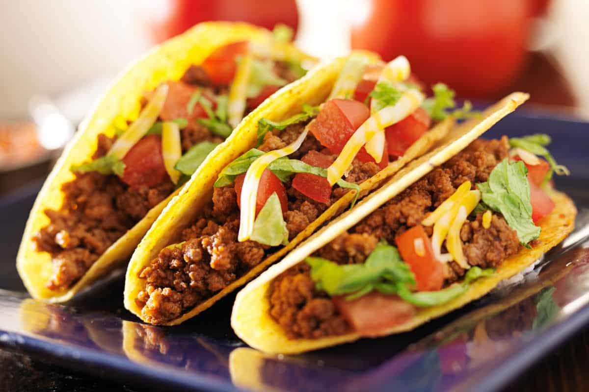 Three standard, hard shell tacos on a plate.