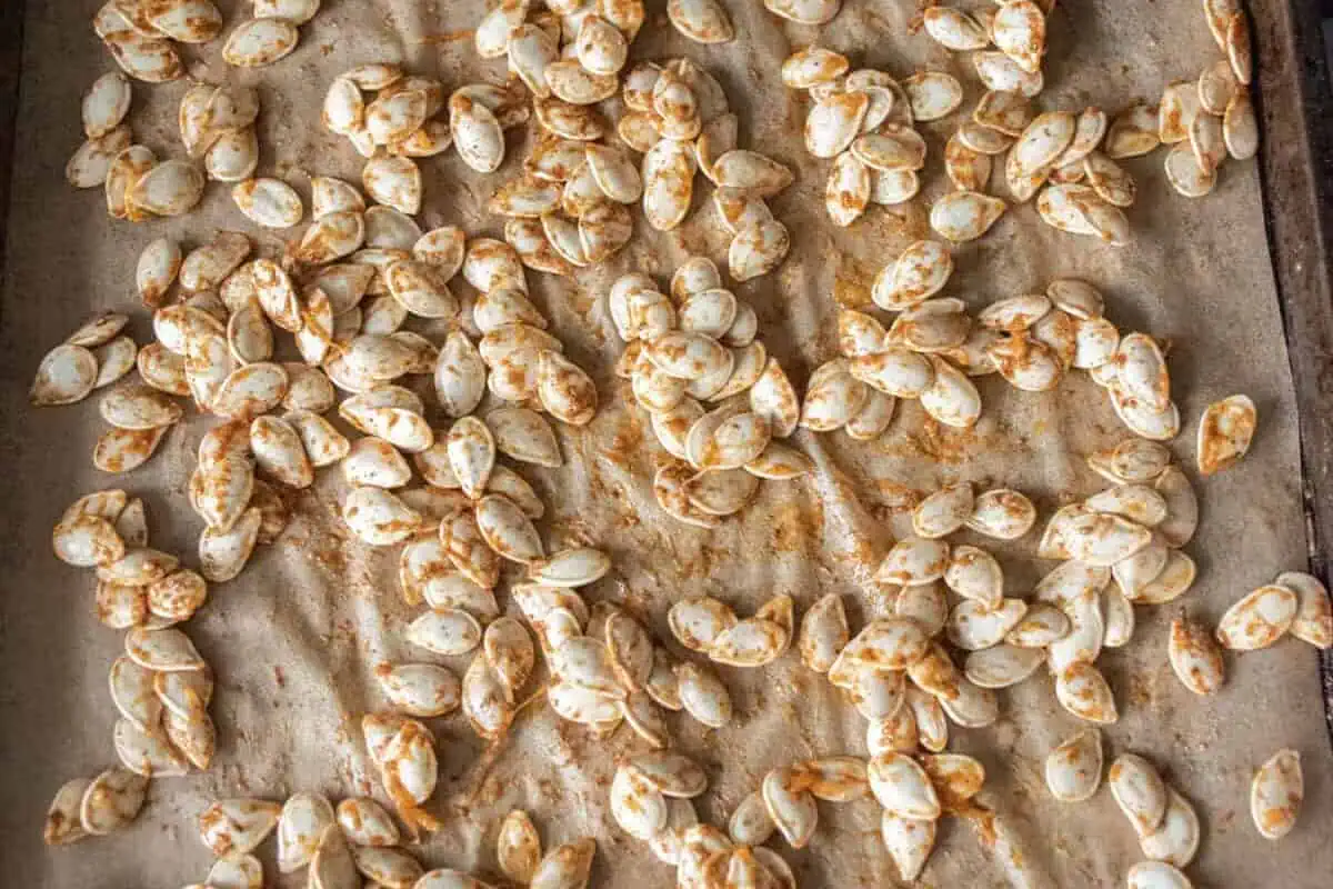 Roasted pumpkin seeds on a lined baking sheet.