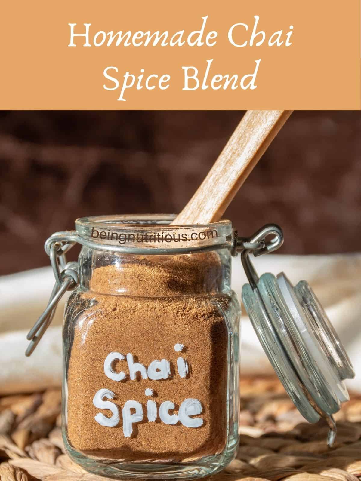 Chai spice mix in a small jar with a wooden spoon in it. Text overlay: Homemade Chai Spice Blend.