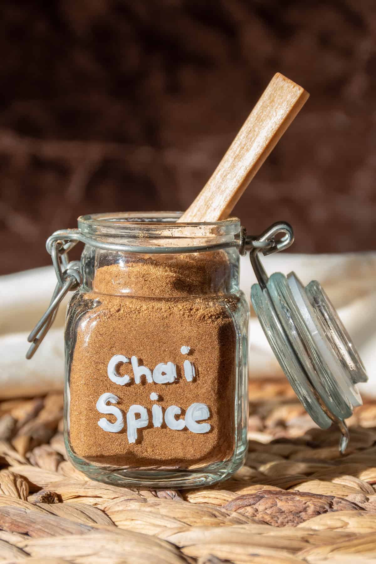 Chai spice blend in a small jar with a wooden spoon in it.