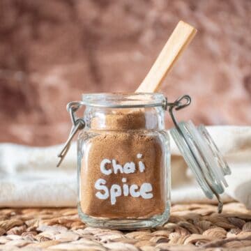 Chai spice mix in a small jar with a wooden spoon in it.