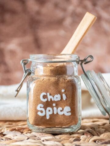Chai spice mix in a small jar with a wooden spoon in it.