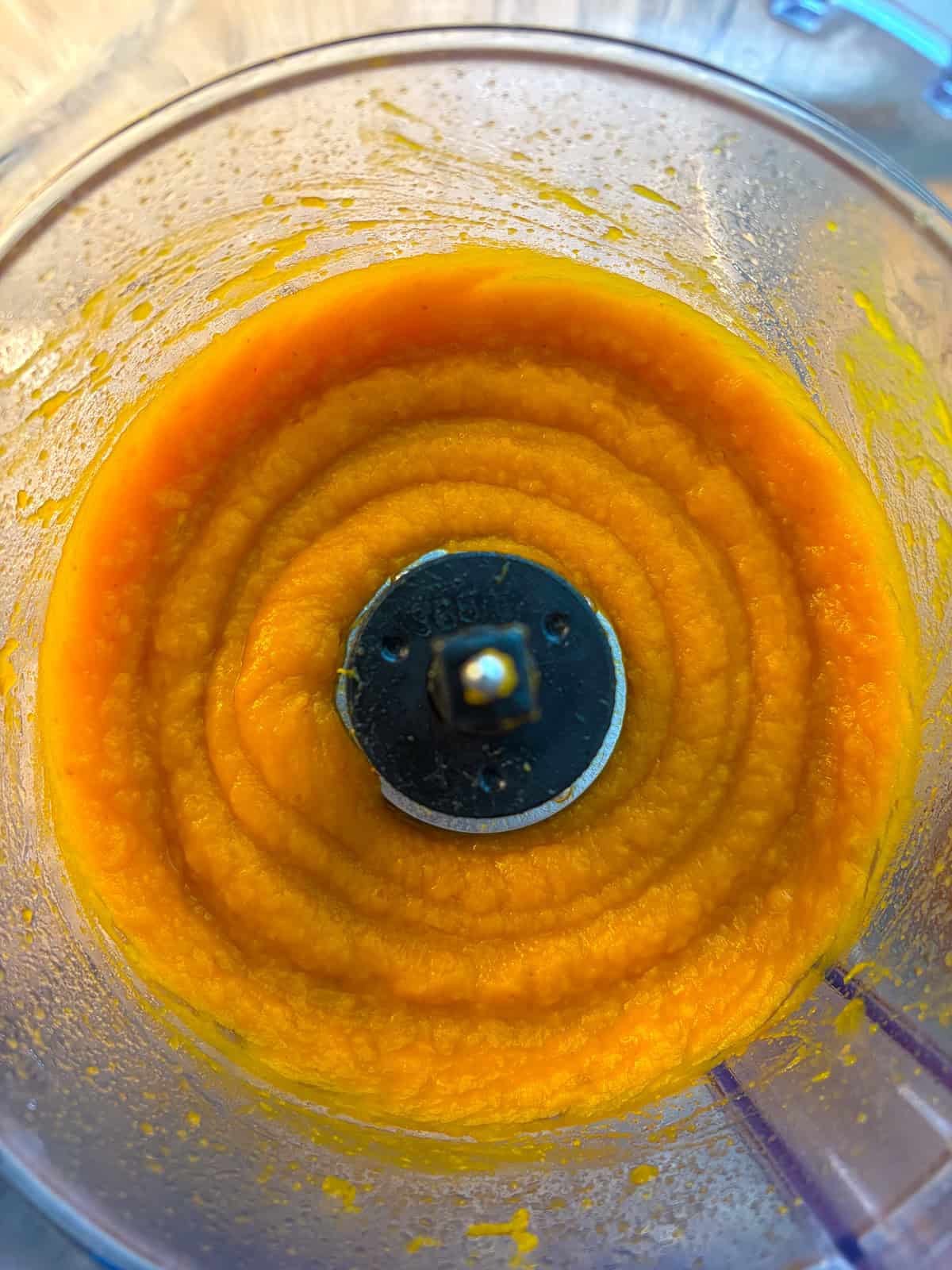 Pureed pumpkin in the bowl of a food processor.