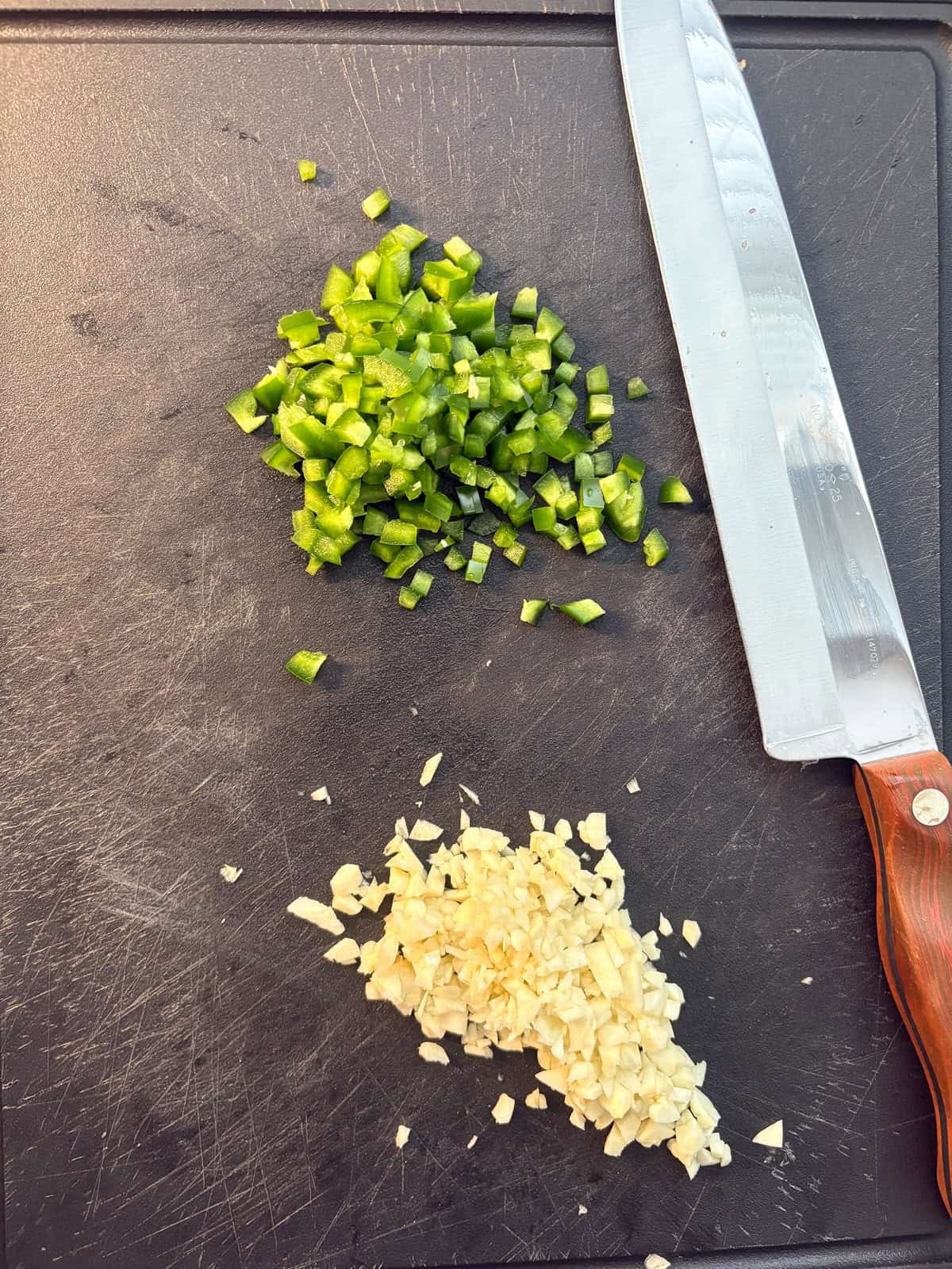 Minced garlic and jalapeño on a cutting board.