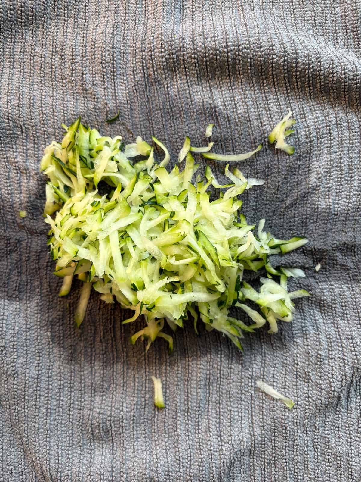 Shredded zucchini on a dish towel, after being squeezed out.