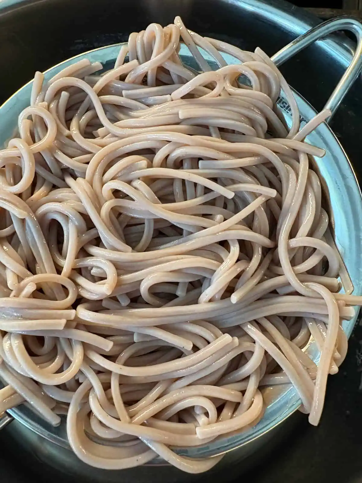 Cooked, drained, and rinsed soba noodles in a strainer.