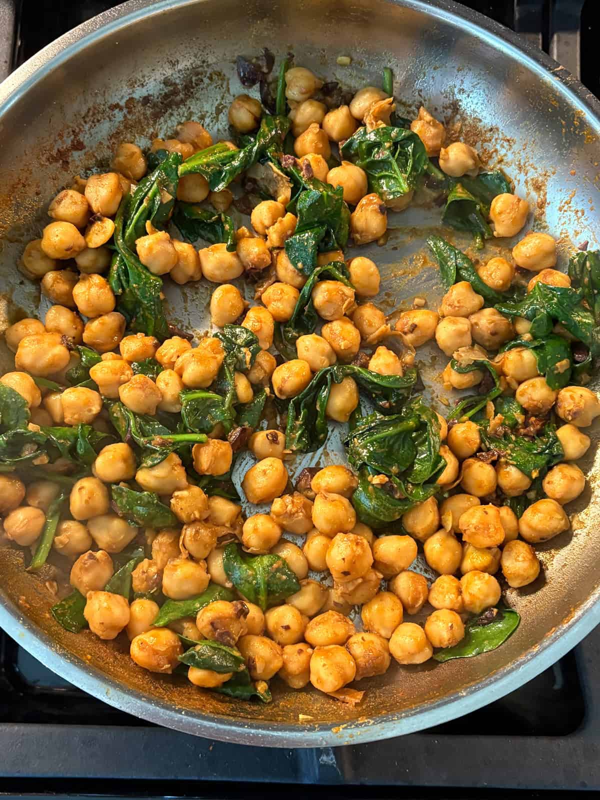 Sautéed chickpeas and spinach in a pan.