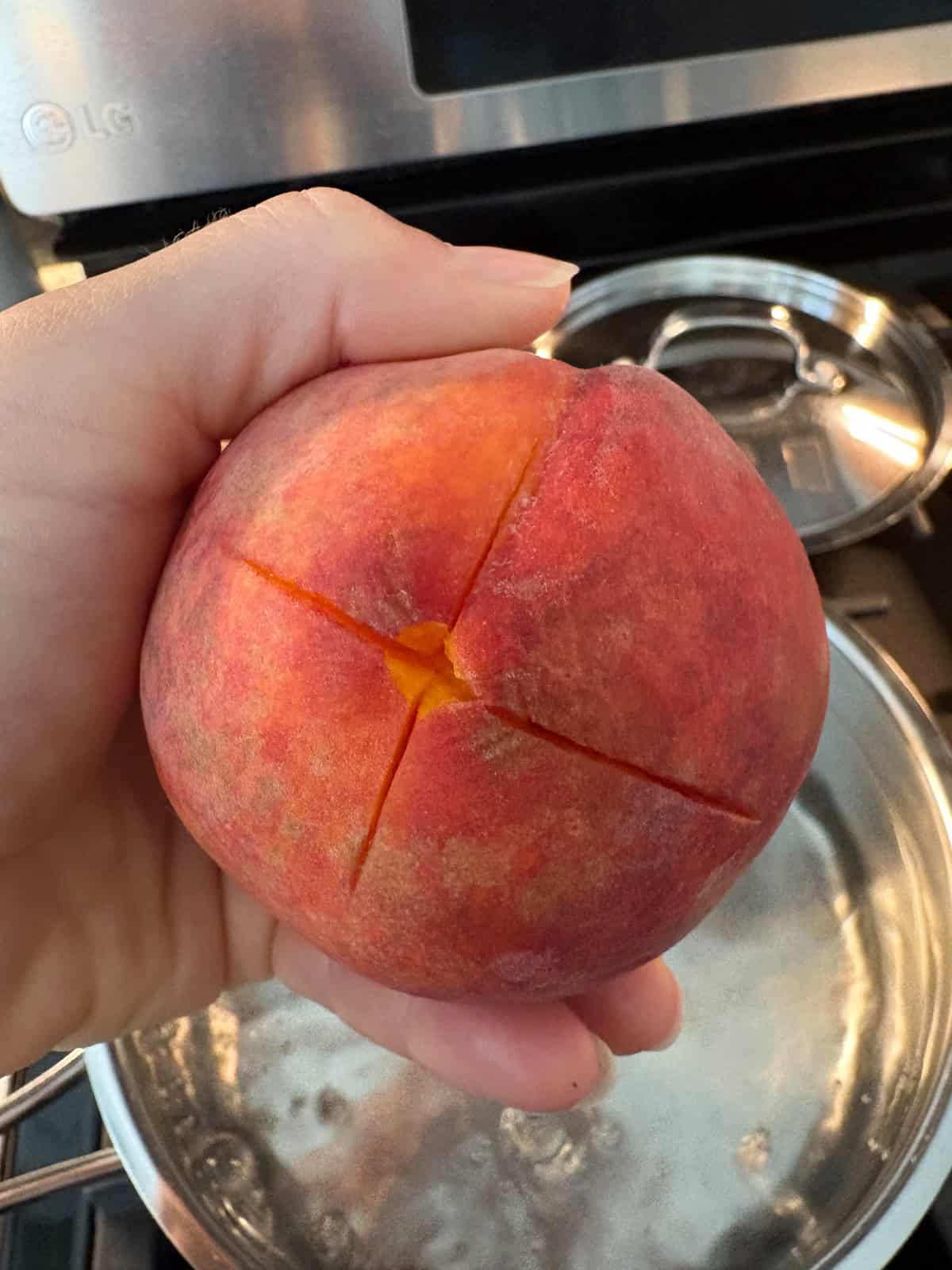 Visual of the "X" cut into the bottom of the peach before blanching.