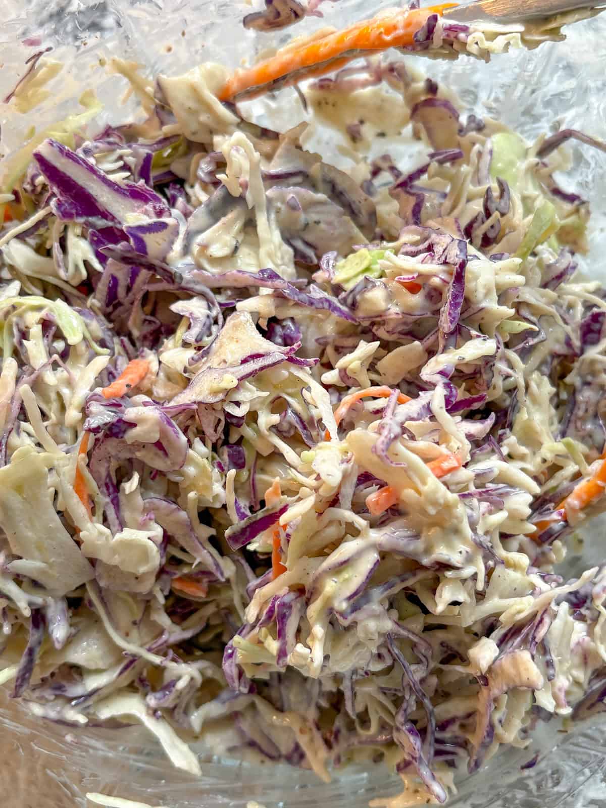 Coleslaw dressing mixed into the shredded cabbage mixture.