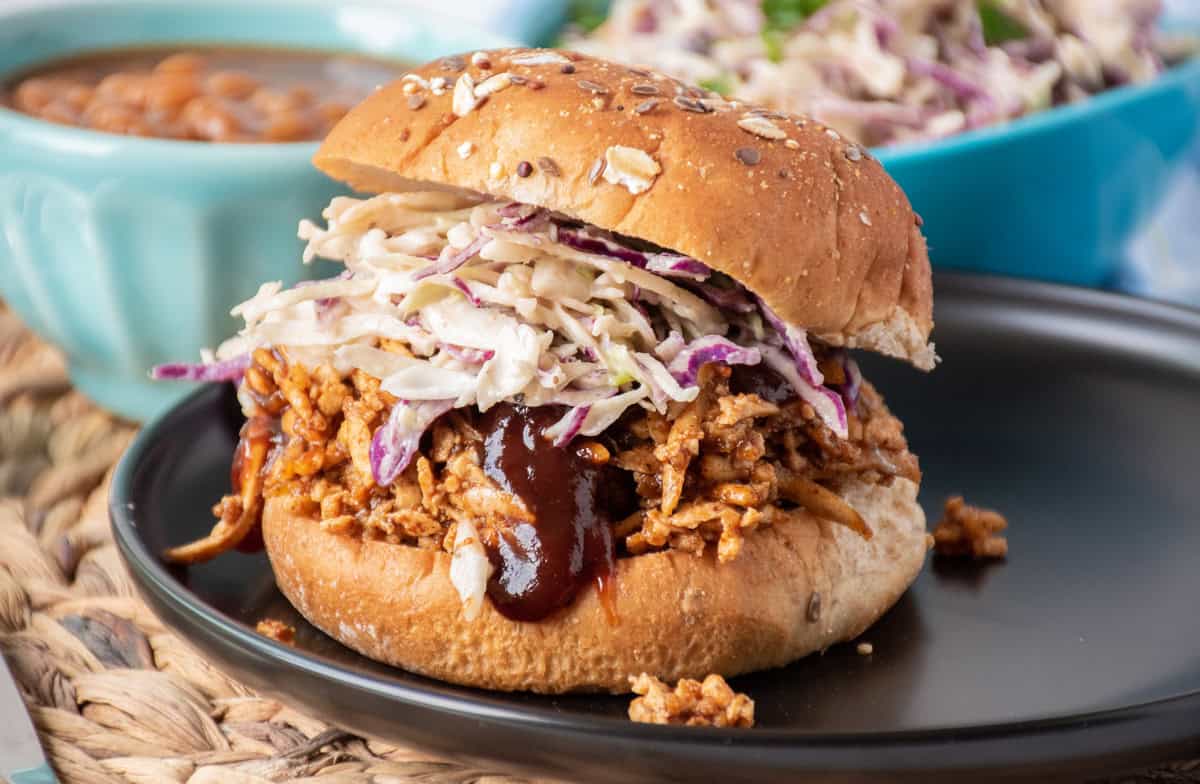 Shredded BBQ tofu sandwich with coleslaw, on a hamburger bun.