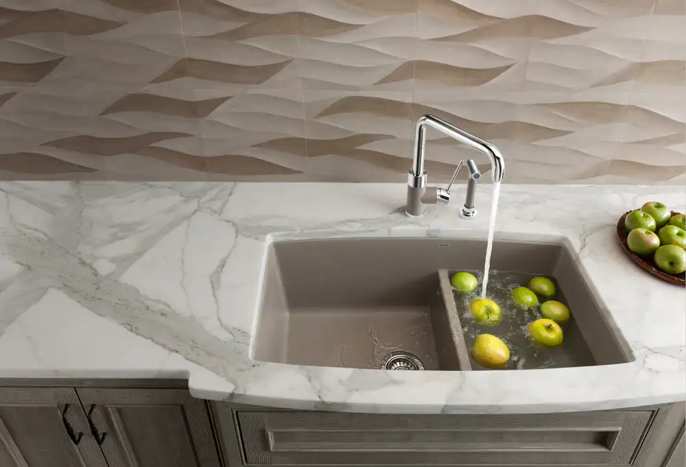 Modern kitchen sink with floating lemons and green apples on marble countertop.
