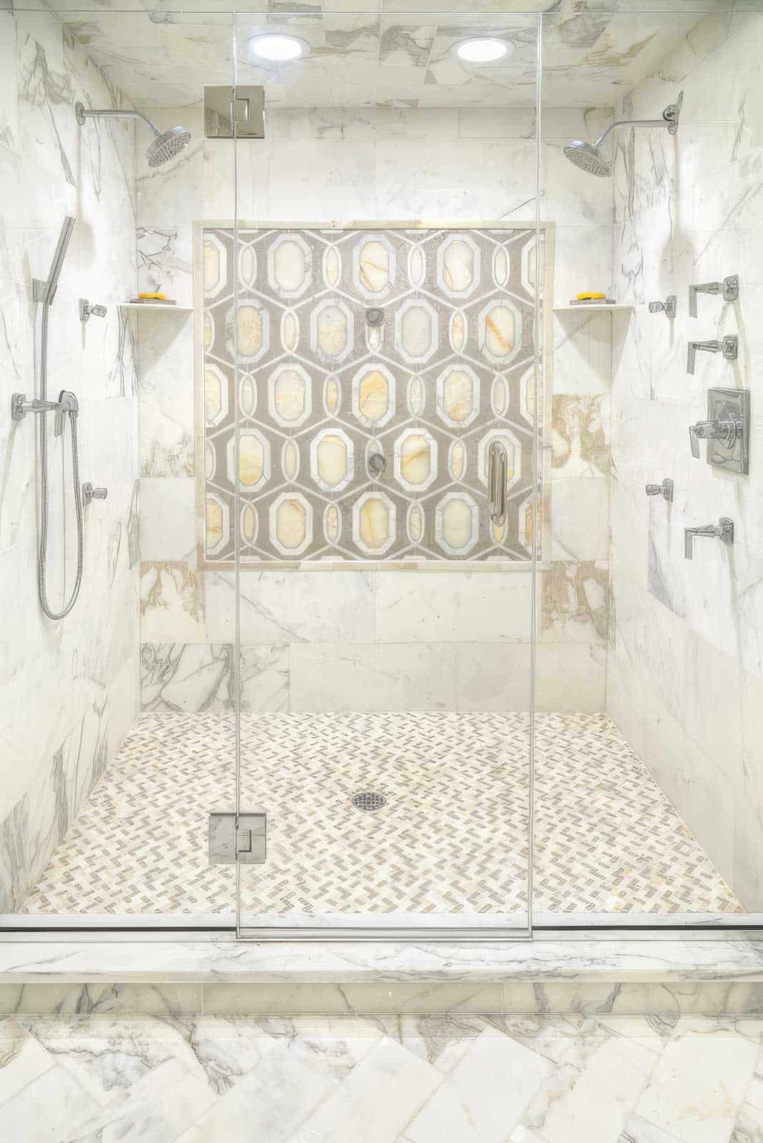 Luxury walk-in shower with marble walls and geometric tile design.